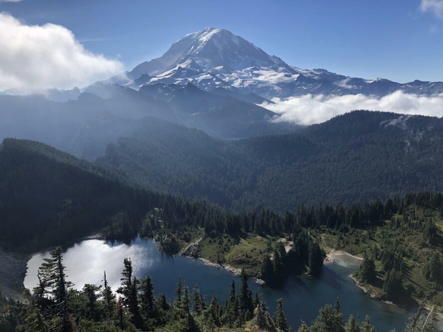 Mount Rainier looms over the forests and alpine lakes below on a clear morning. 