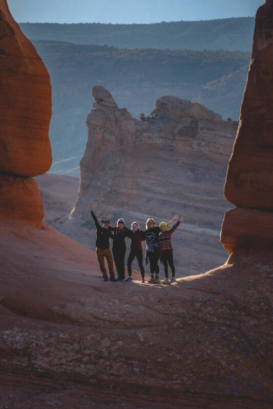 Hikers taking a photo in a window in Arches National Park