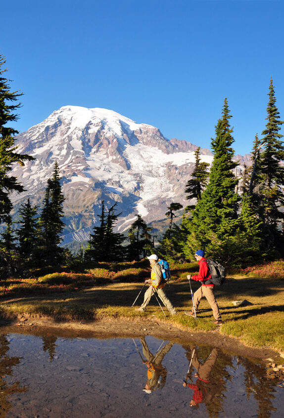 "Two hikers walk by a small pond in Mt. Rainier National Park, Washington State."