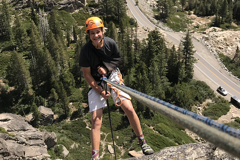 A kid smiling while climbing on Donner Summit