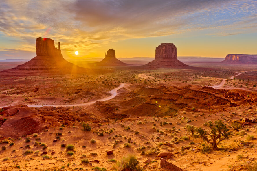 The vast desert landscape around Monument Valley illuminated by sunset light.