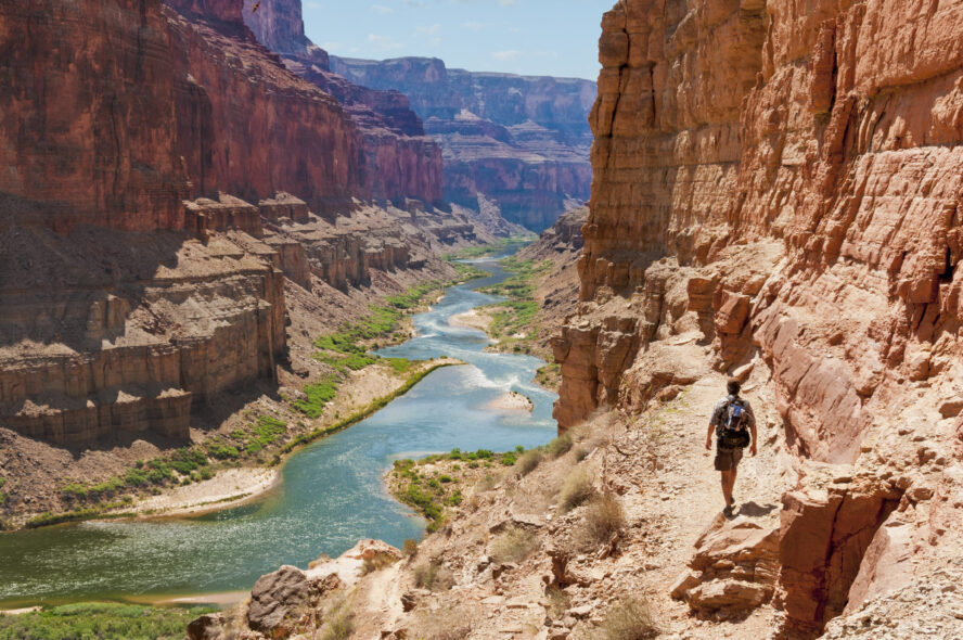 A hiker walks along a trail beside the Colorado River in the Grand Canyon.