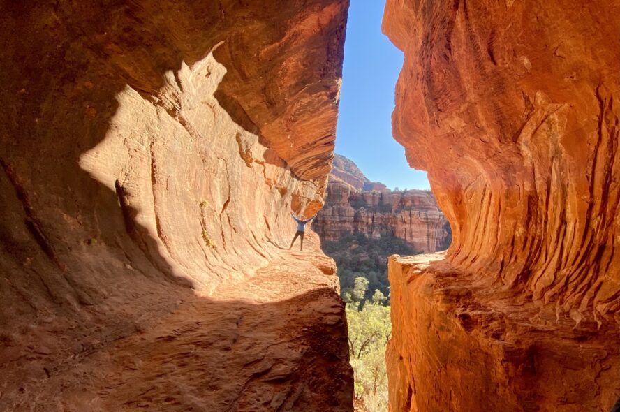 A person standing in the long and wide tubular hole of Sedona’s Subway Cave.