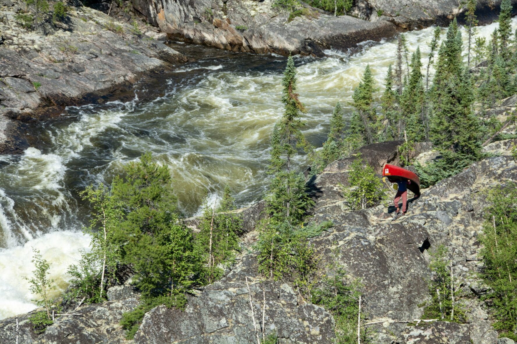 A man carrying a canoe next to the Porcupine River