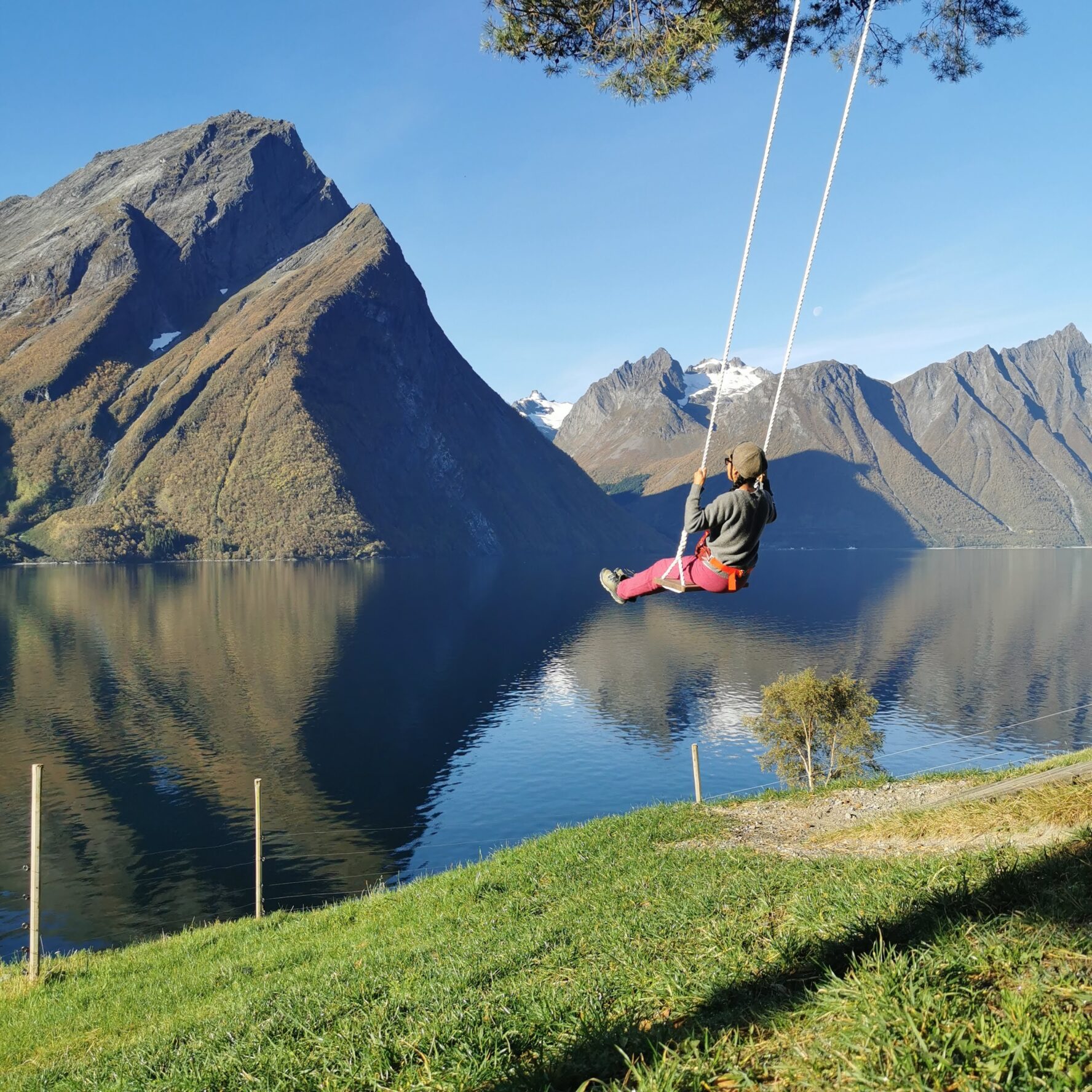 An adventurer on a swingset with a scenic view in Norway