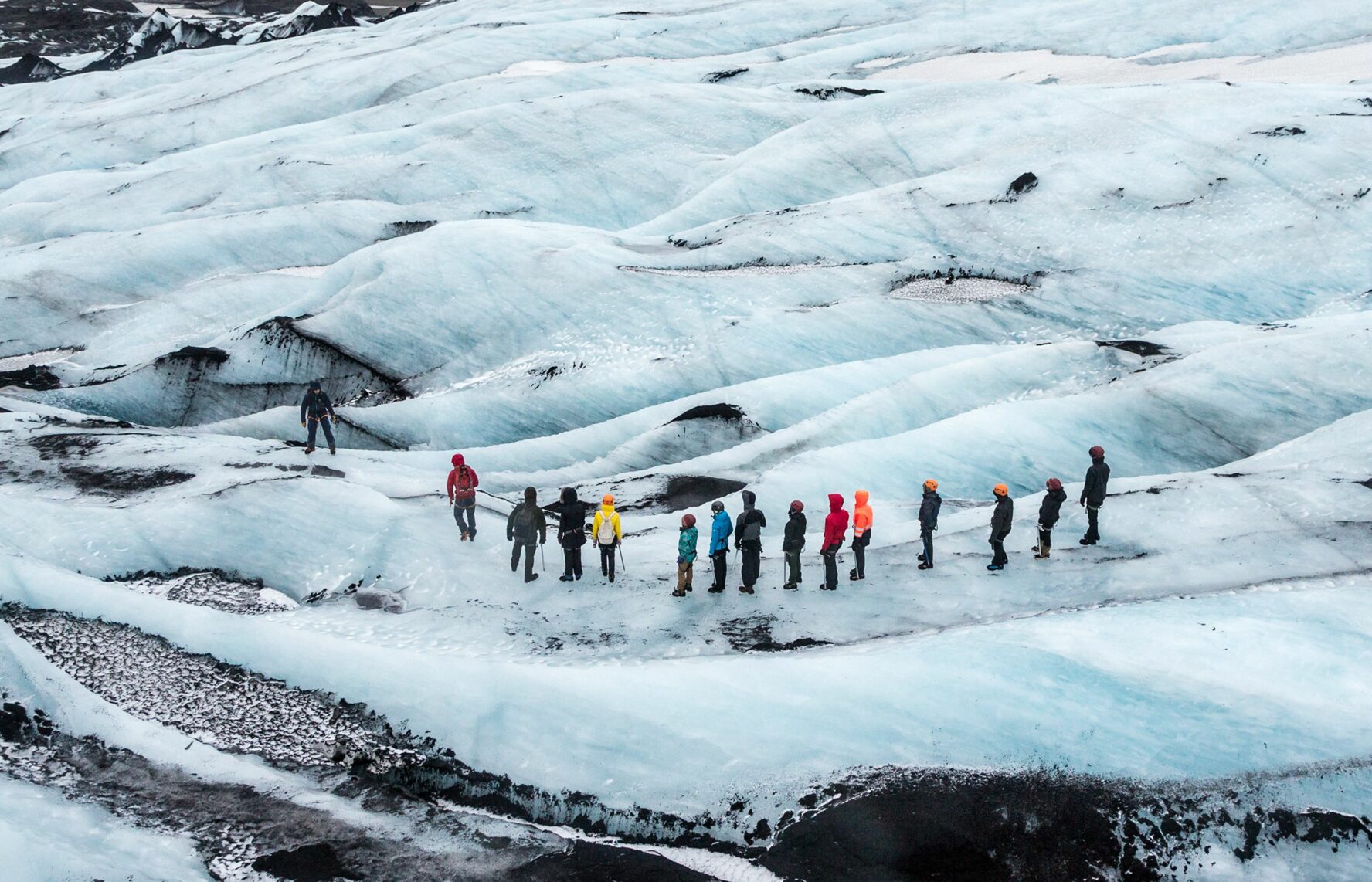 A like of hikers in colourful clothing walking over the icy blue Bilbo glacier