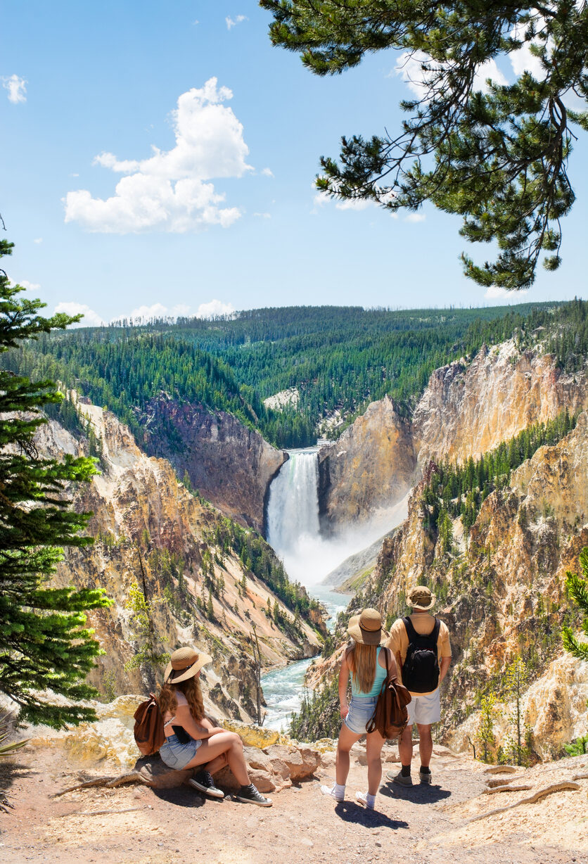 Family relaxing and enjoying beautiful view of waterfall on hiking trip in the mountains. Beautiful Lower Falls at Yellowstone National Park.