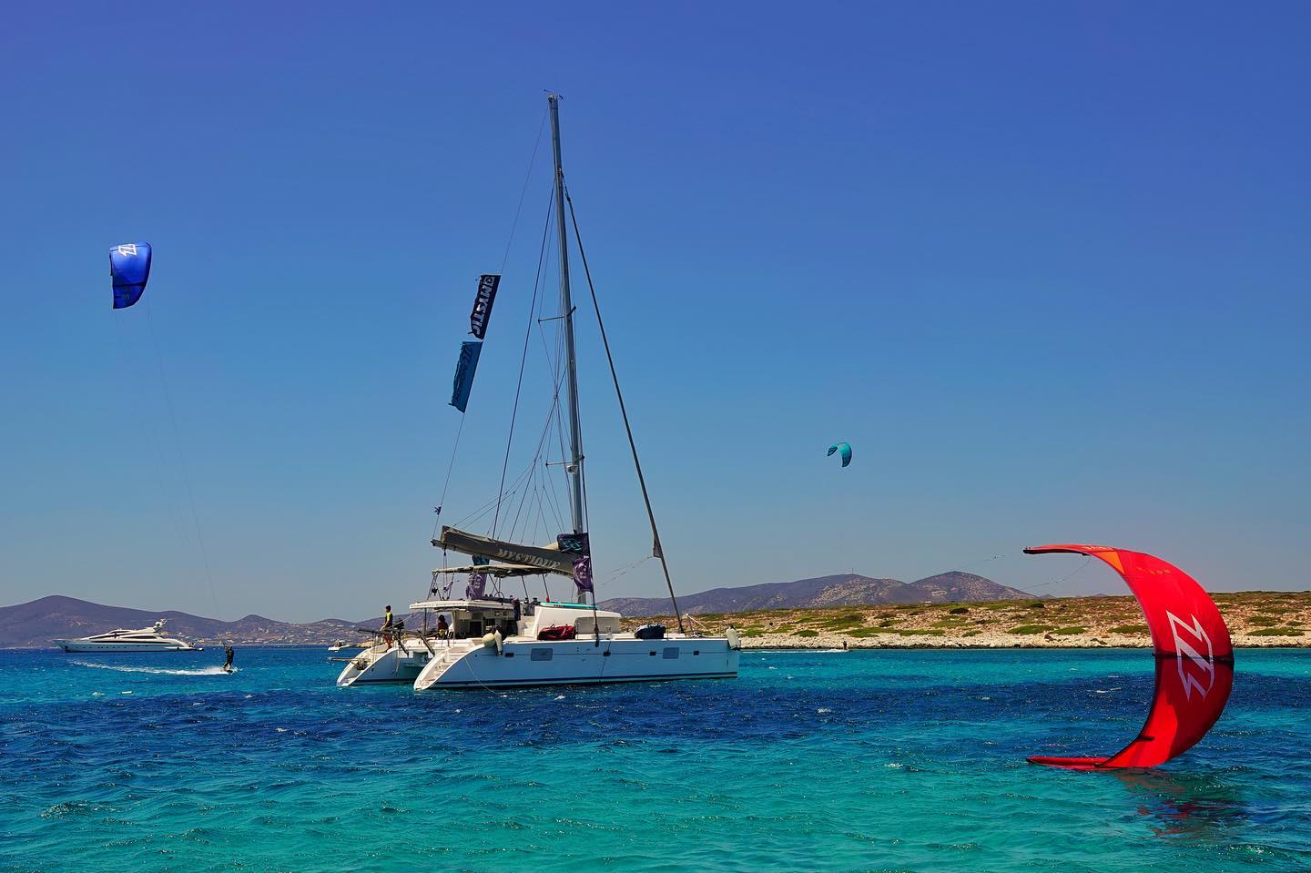 A kitesurfer and a catamaran in the Cyclades, Greece