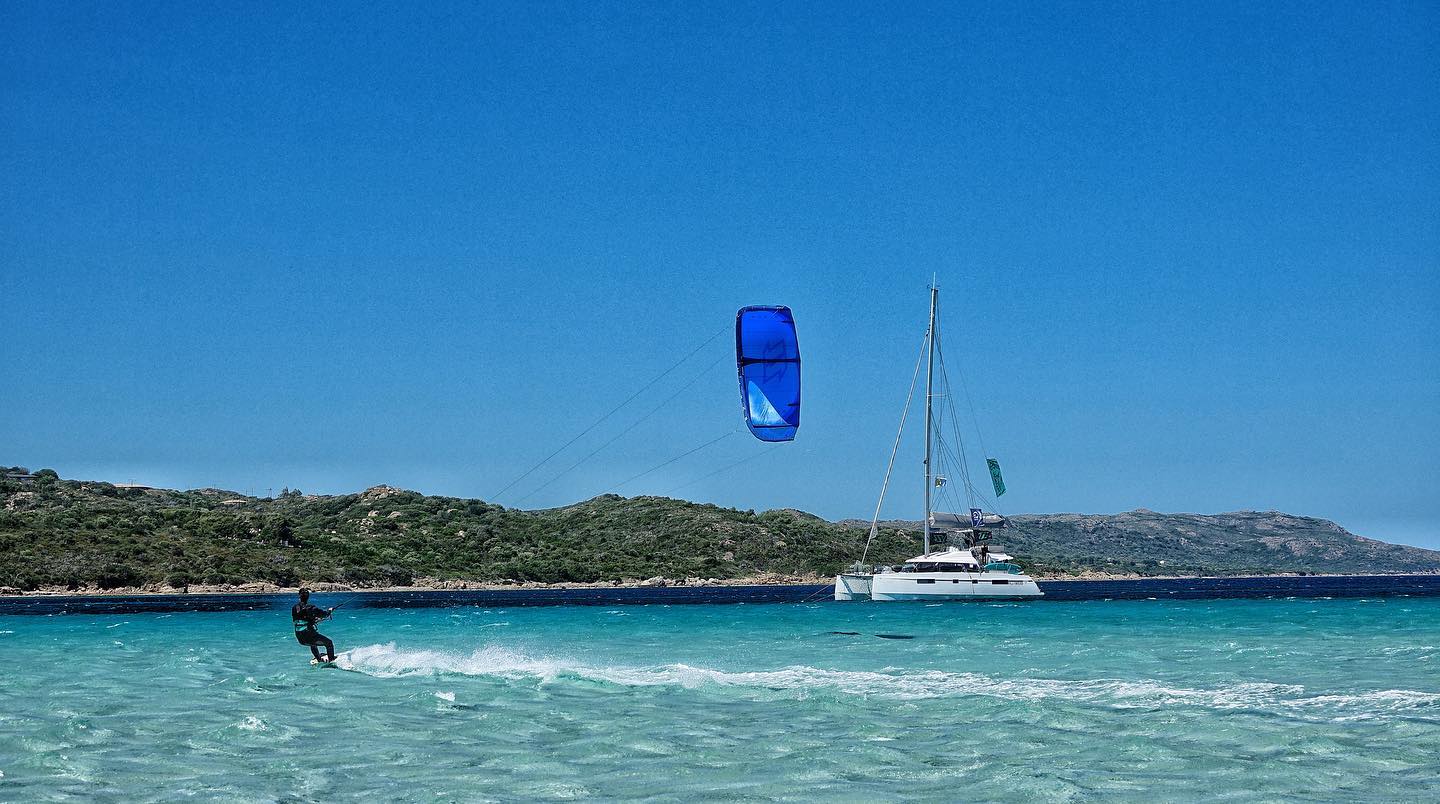 A kitesurfer and a catamaran in Sardinia
