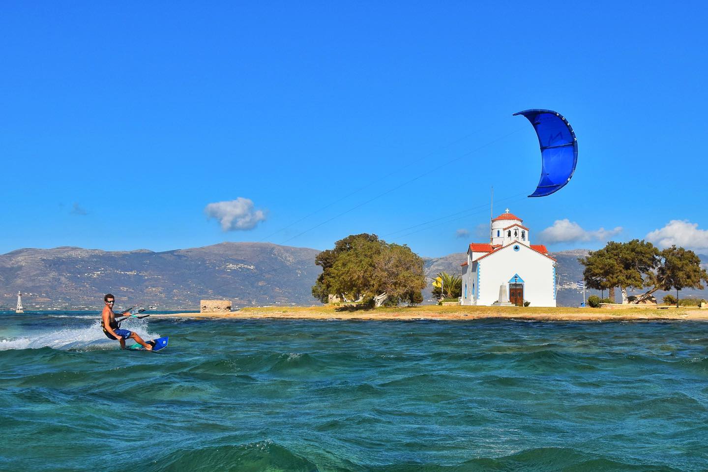 A kitesurfer gliding over the water in the Cyclades, Greece