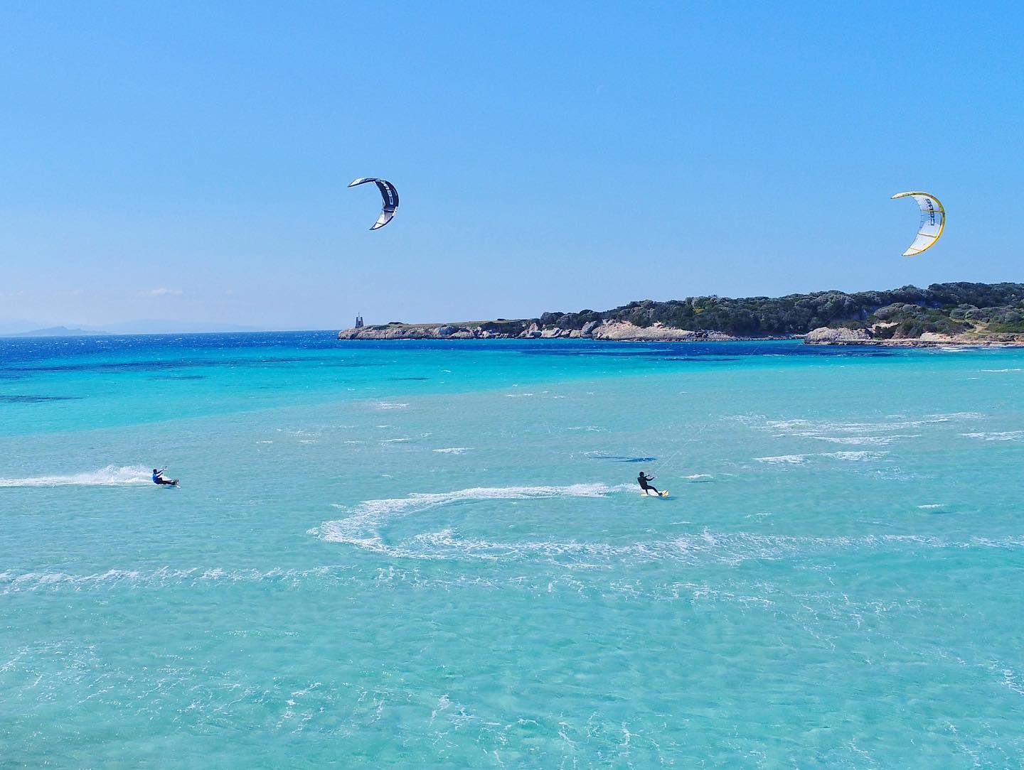 Kitesurfers in Sardinia on the turquoise sea