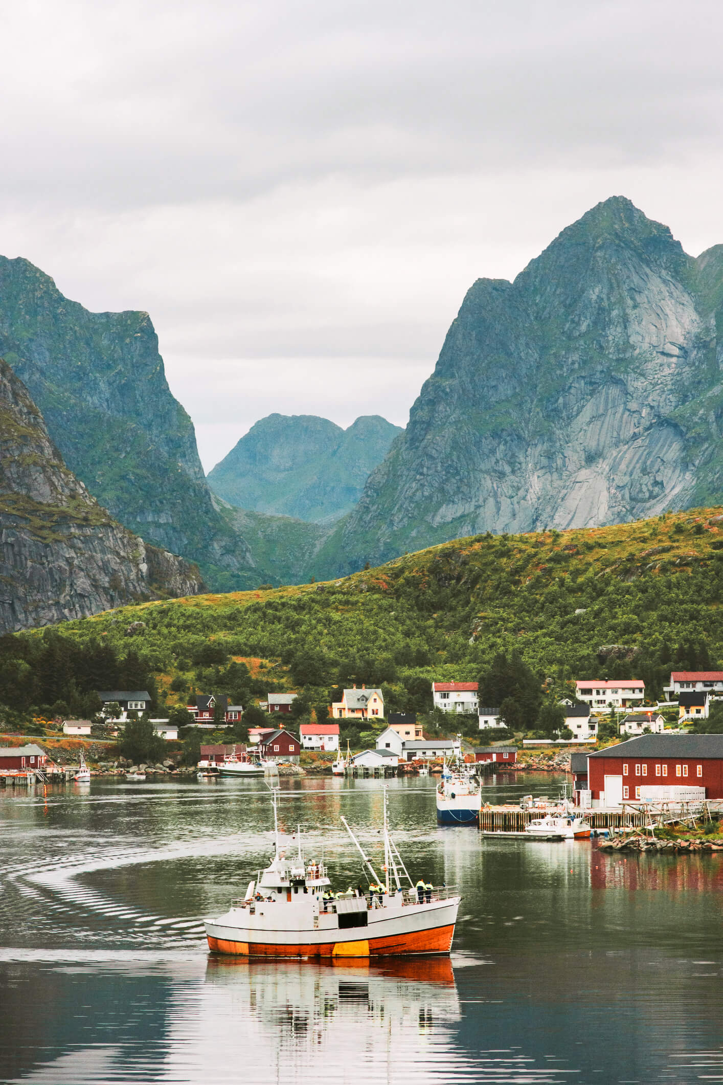 A boat in the docks of Lofoten is just a small figure compared to a mountain overlooking the town.