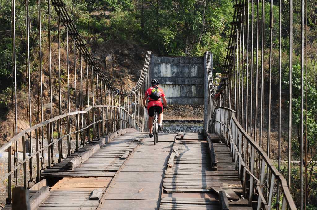Mountain biker cycling across a bridge, Sikkim