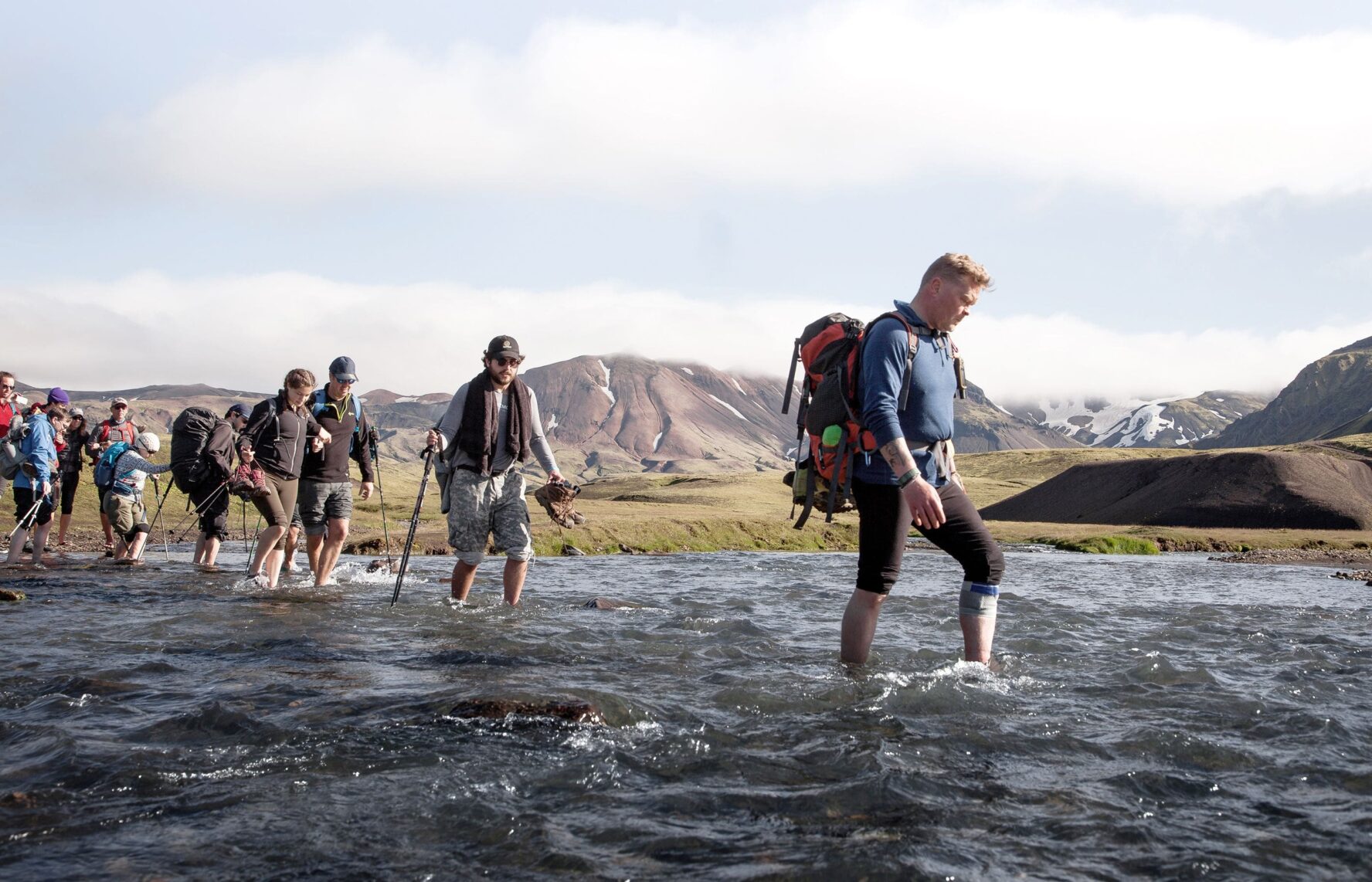 Hikers wading through a shallow river