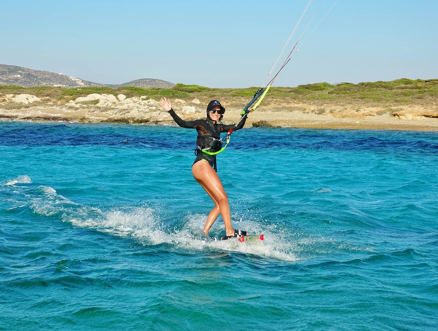 A woman smiling and waving at a camera in the Cylcades