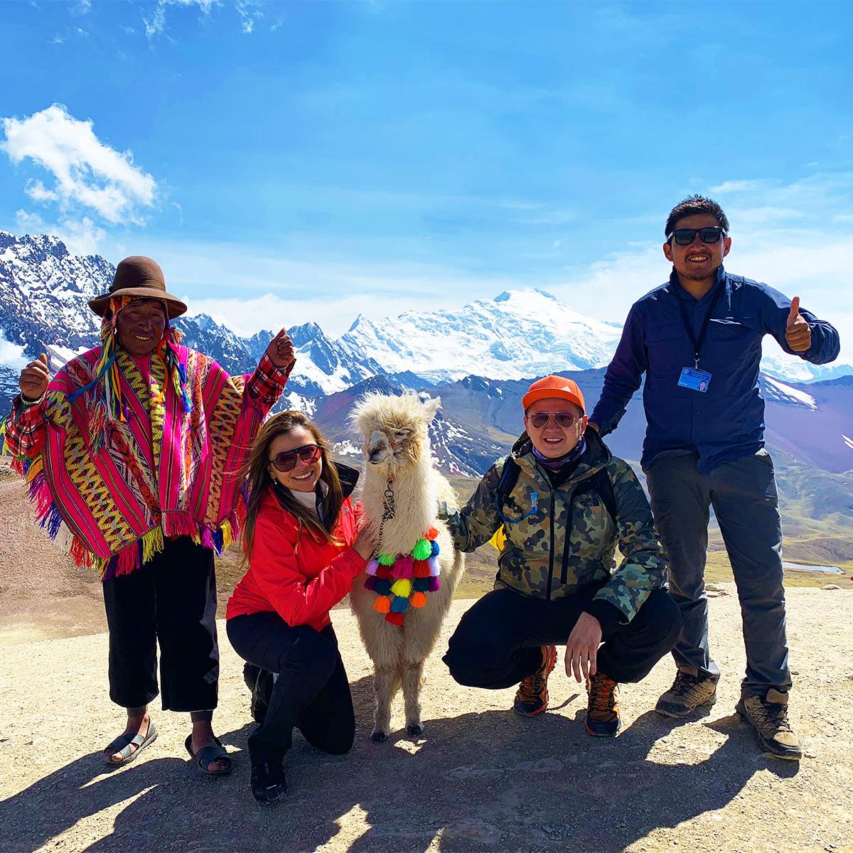 Hikers posing with a llama and a man in traditional costume