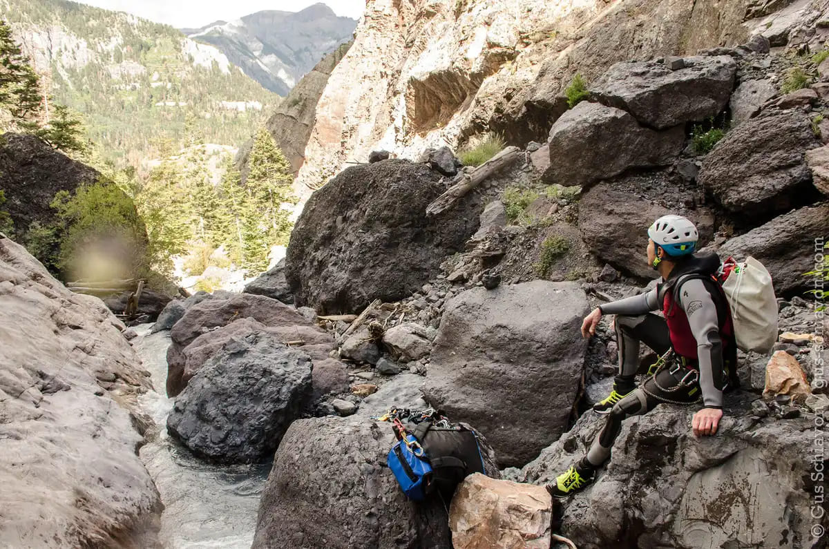 A person sitting on rock in Bear Creek and watching the river rushing through the canyon