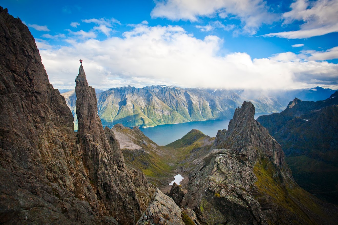 A climber posing on a scenic peak in Southern Norway
