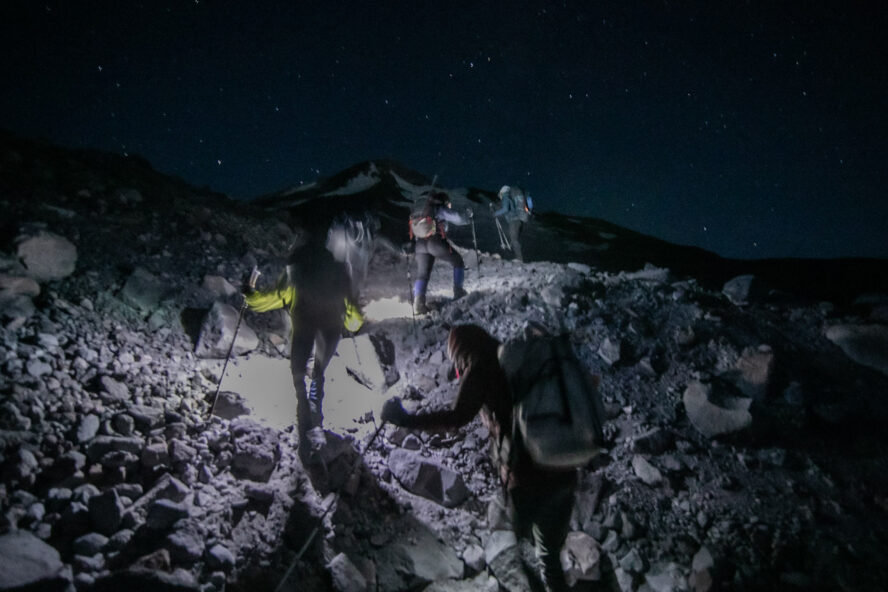 A group of mountain climbers push towards the summit of Mount Shasta in the early dawn.