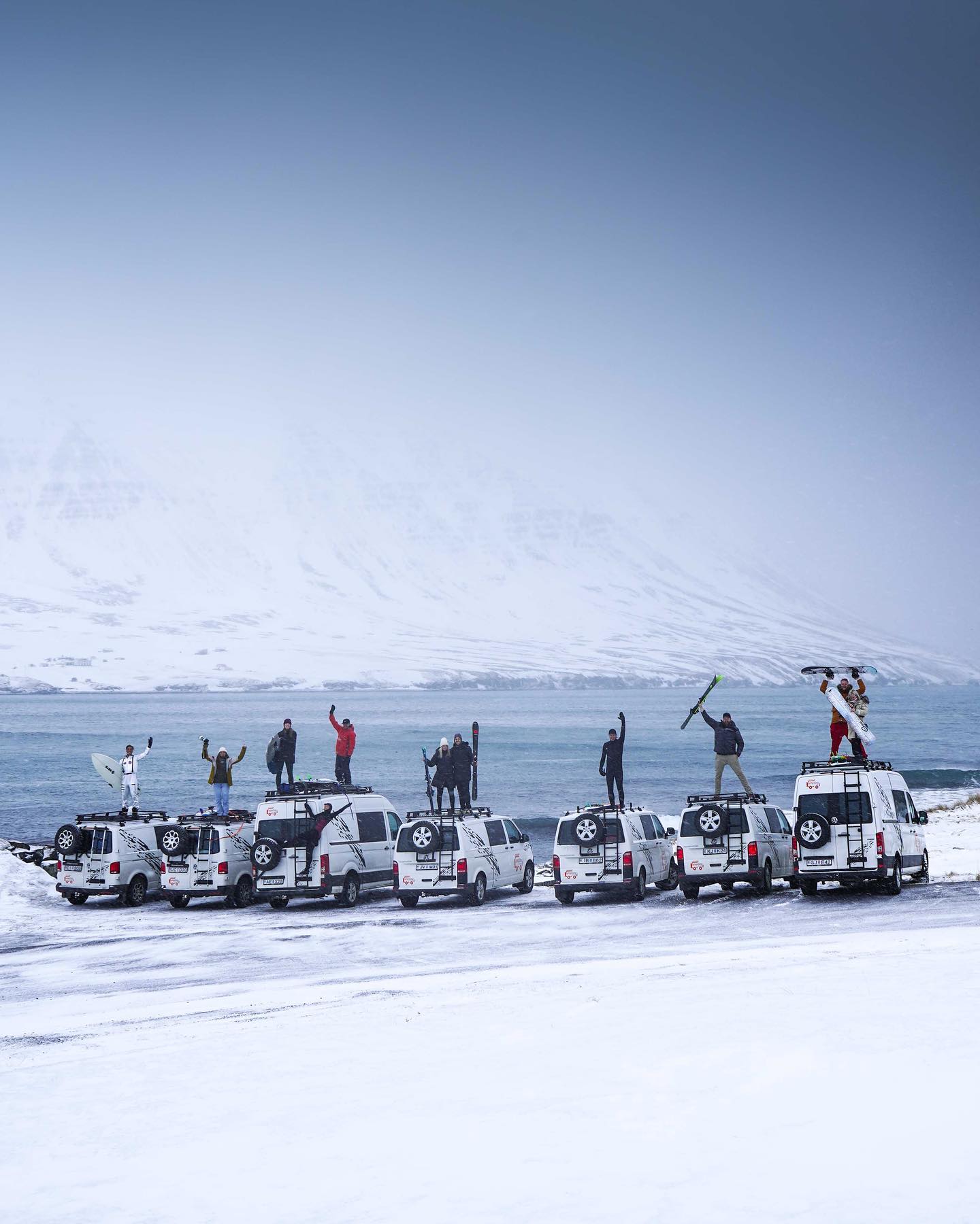 A group of skiers standing atop of vans.