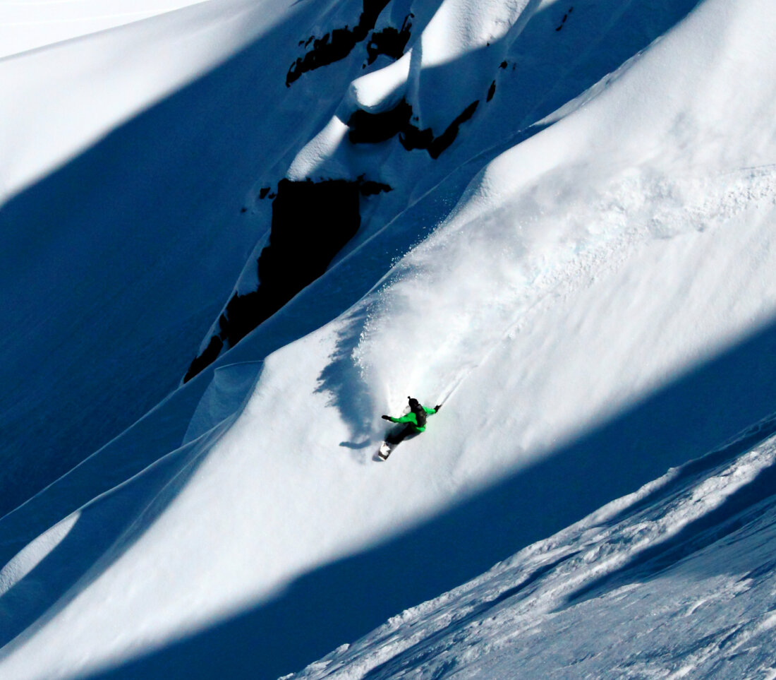 A person skiing down a steep mountain face.