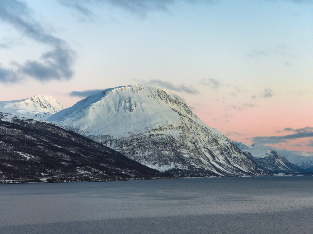 View of the Lyngen Alps from the sea during sunset.