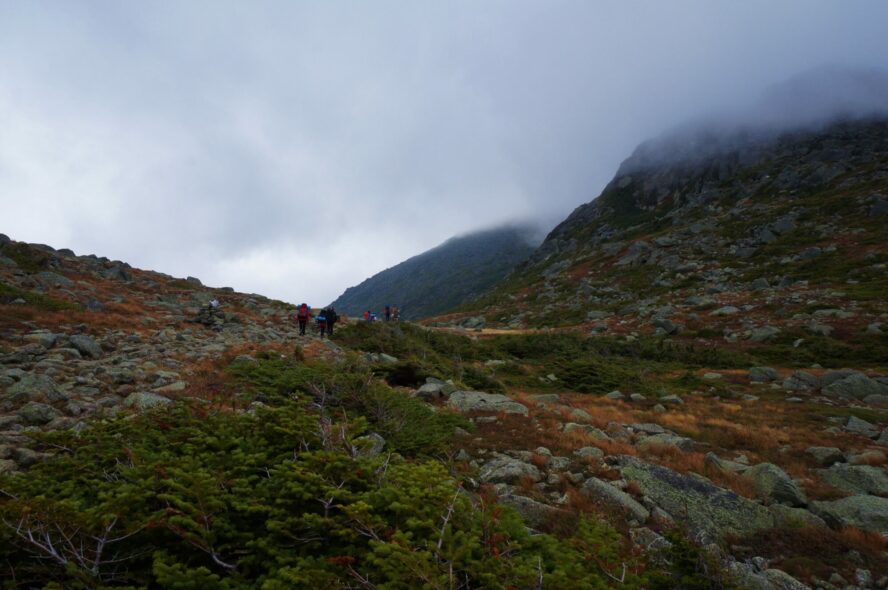  A group of hikers on the Presidential Traverse as clouds roll in through the mountain pass.