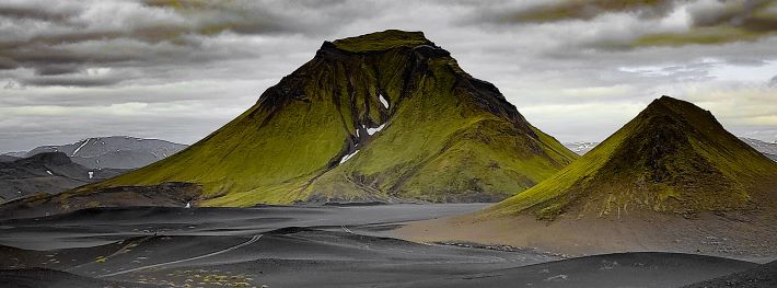 Moss green mountains encircled with black sand deserts