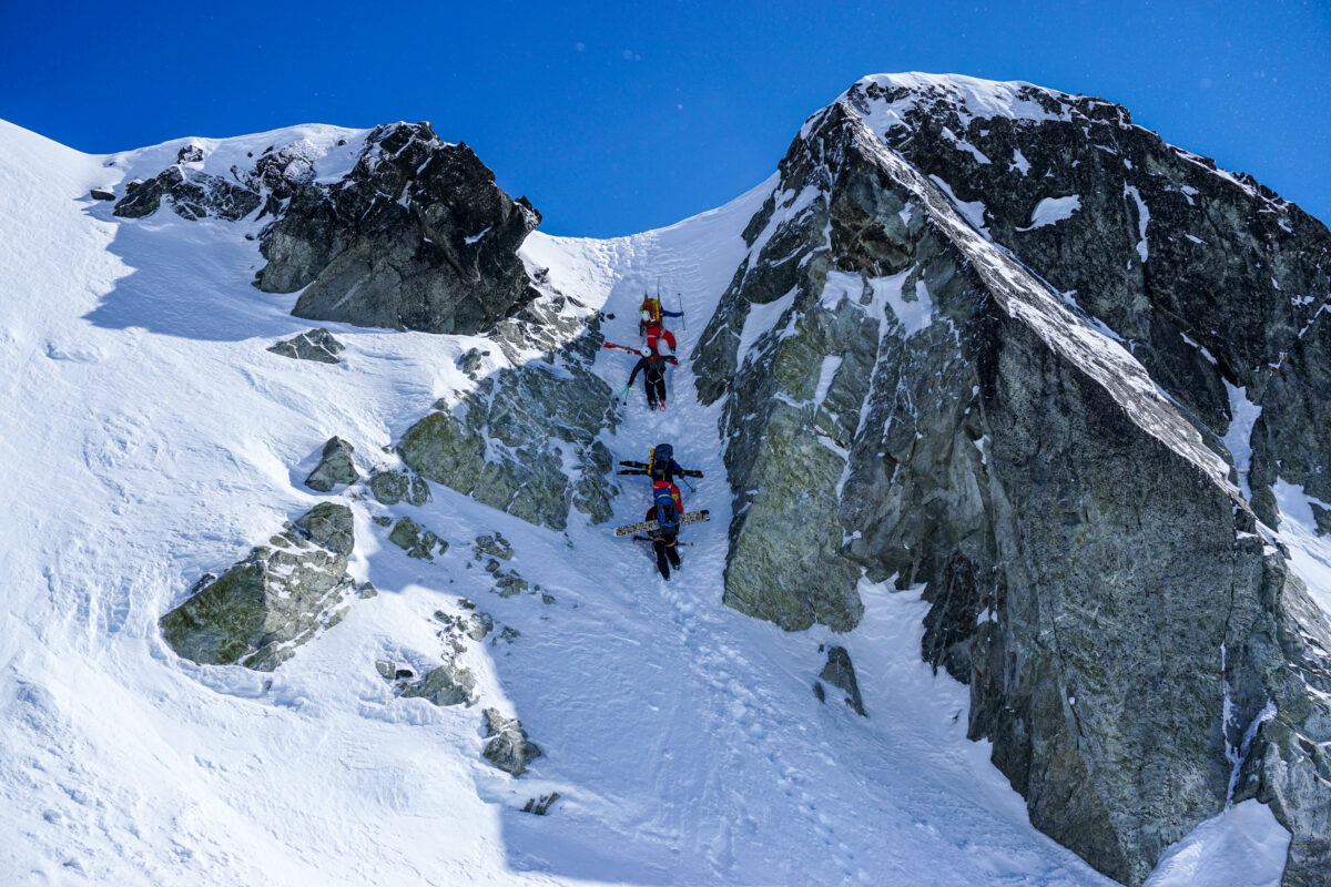 A couple of skiers going down a ridge