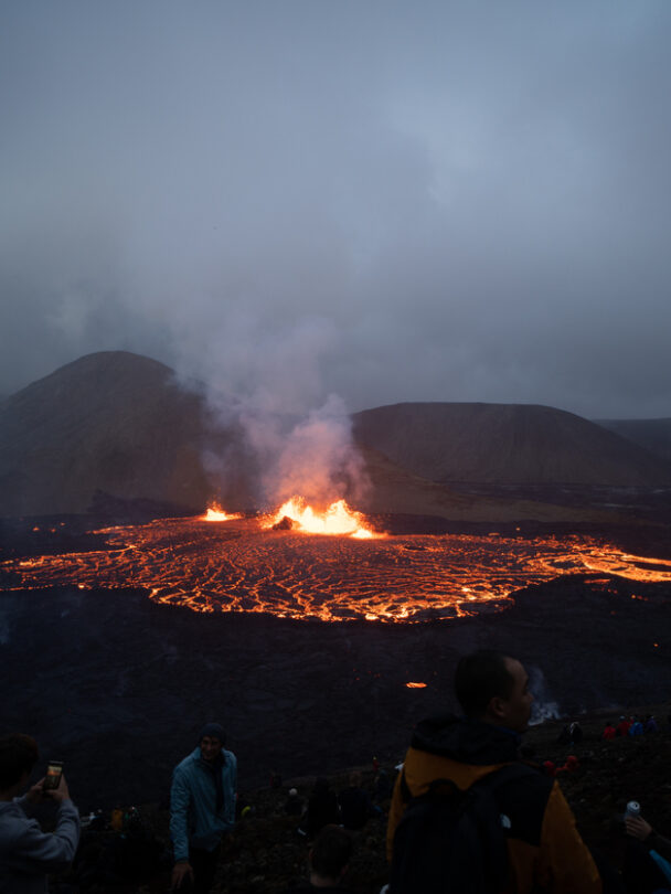 A woman hiking beside the firmed up lava close to the site of an erupting Iceland volcano.