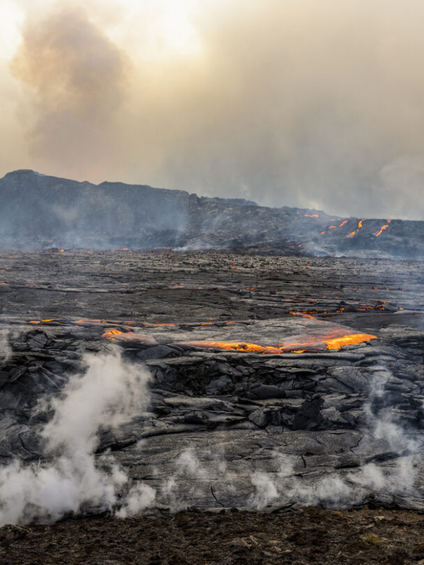 A woman hiking beside the firmed up lava close to the site of an erupting Iceland volcano.