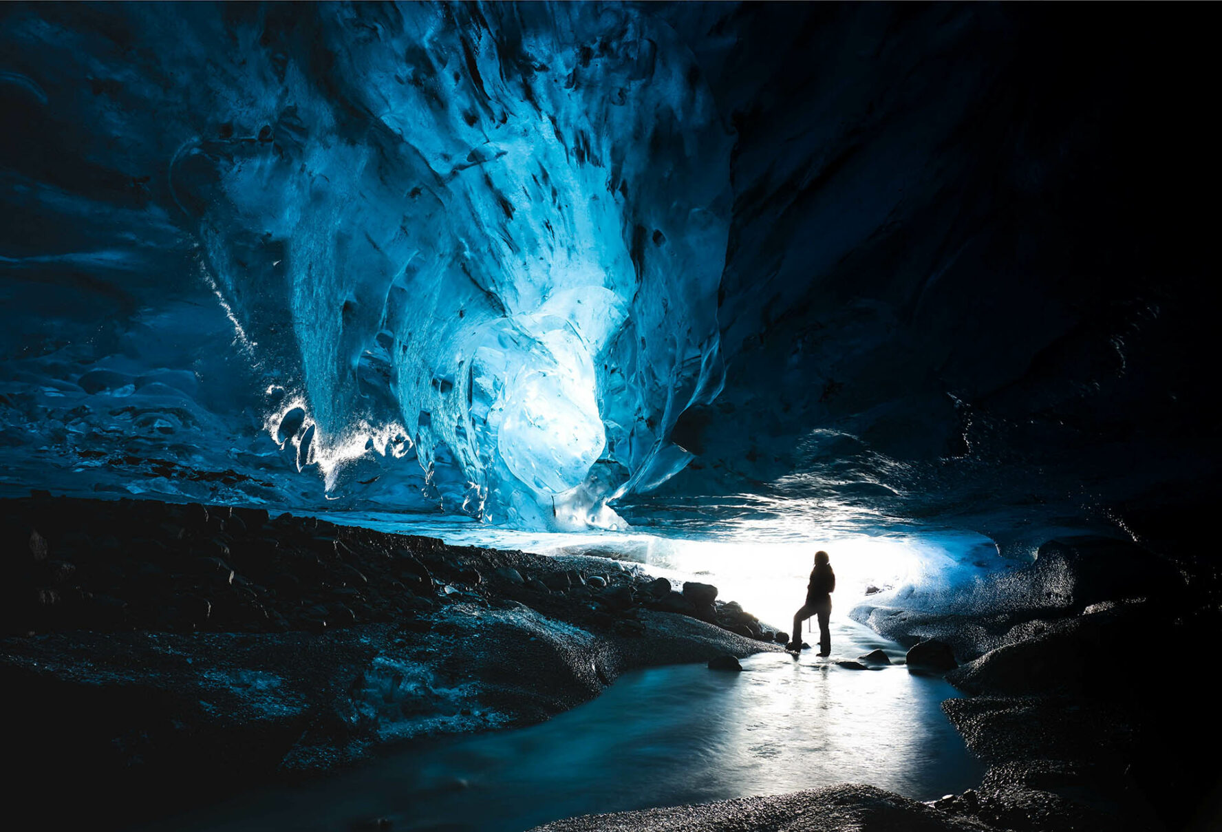 A person observing blue colors in the ice cave located in Iceland.