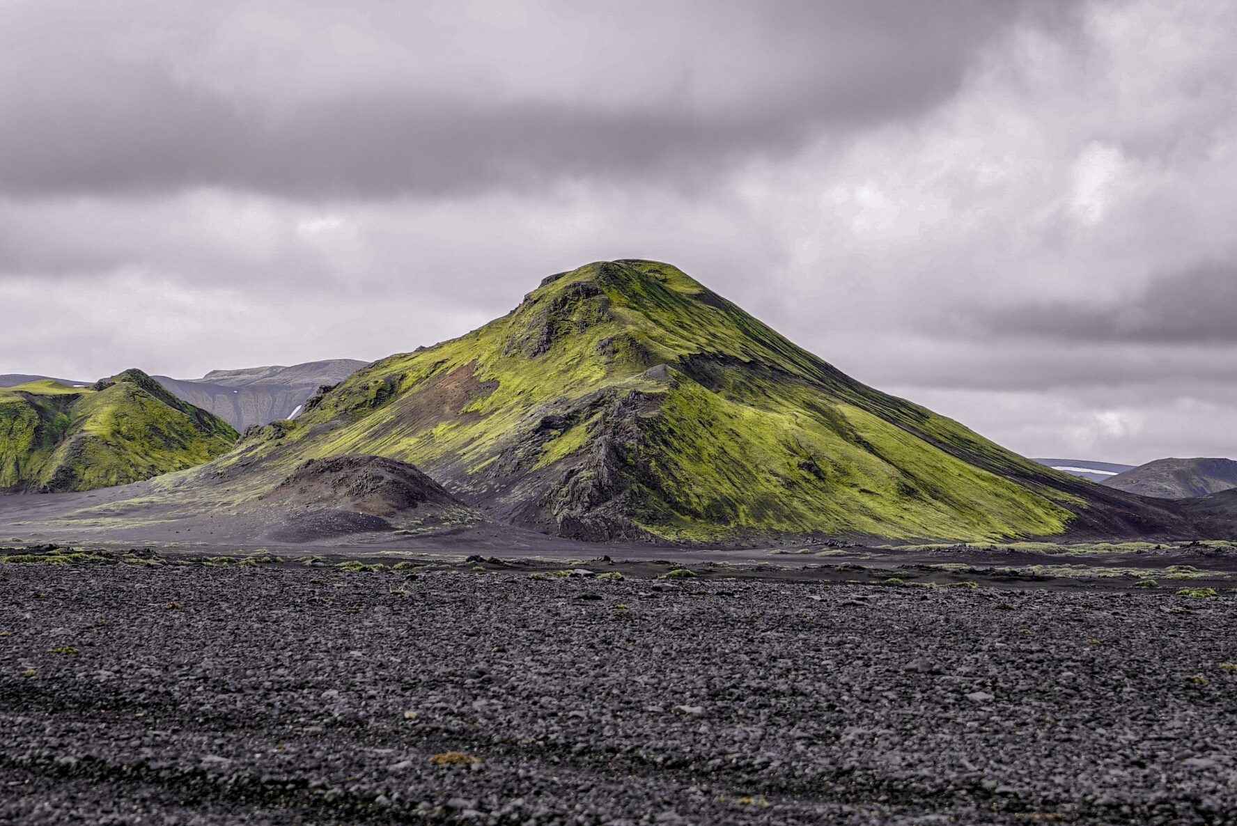 Mossy hill in the center of a black sand desert