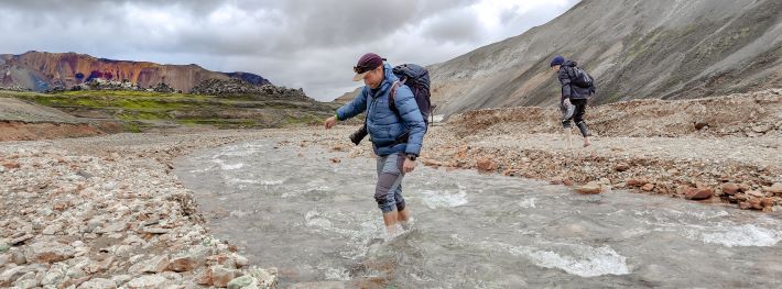 Hikers wading through a river in Iceland