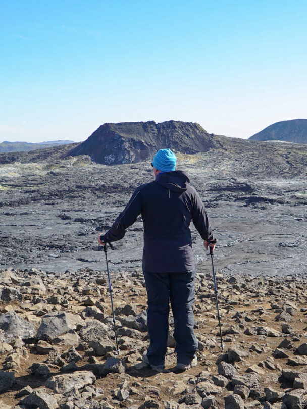A woman hiking beside the firmed up lava close to the site of an erupting Iceland volcano.