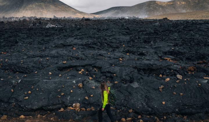 A woman hiking beside the firmed up lava close to the site of an erupting Iceland volcano.