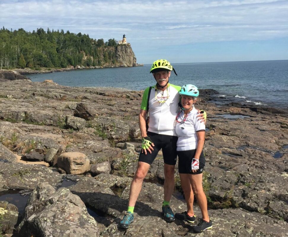 Two cyclers standing on a lake’s shore.