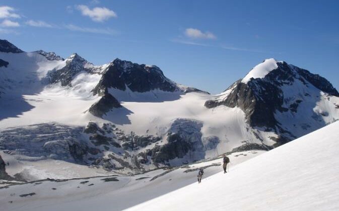 Two trekkers on an exposed, steep section of the Haute Route Glacier Trek, Switzerland.