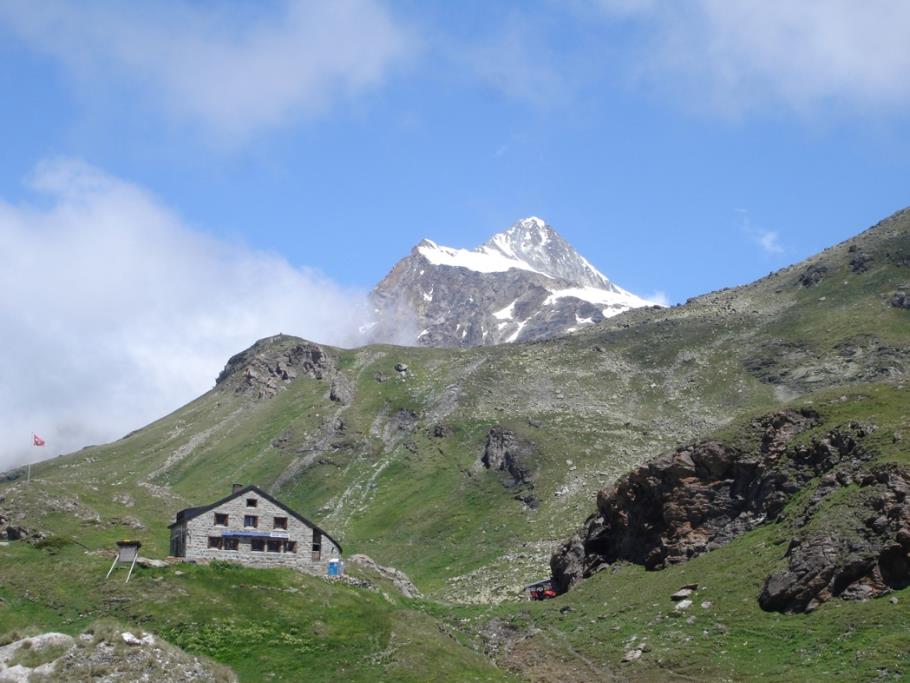 A mountain hut at the foot of a glaciated peak in the Swiss Alps.