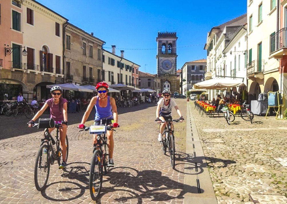 Three cyclists on a street of Italian town